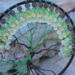 6 inch black yarn wrapped hoop cradles black and green wire tree of life, adorned with black and shades of green frosted glass beads. 