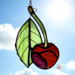 Cherry stained glass ornaments made or varying shades of red and green glass. Backdrop is of a blue sky with white puffy clouds on a sunny day.