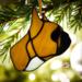 French Bulldog Stained Glass ornament made of tan colored glass, hanging on from a Christmas tree branch with white lights in the background.