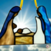 Nativity stained glass ornament, shown here with brown skin. Mary is made with white and blue glass, manger is made with brown glass, baby Jesus has white swaddling, Joseph is made with brown and purple glass.
