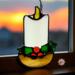 Candle stained glass ornament- candle is made with white glass and has a yellow flame with a brown base. A little holly with two leaves and three red berries sits at the base.