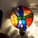 Dragonfly Stained Glass Night Light- in green and blue iridescent glass with yellow, orange mottle glass backdrop. Shown lite.