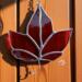 Red Maple Leaf stained glass ornament hanging on a barn wall.