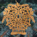 A handcrafted Victorian-style wooden Christmas tree ornament shaped like a basket filled with intricate floral designs, featuring detailed leaves and blossoms, with a small hook at the top for hanging.