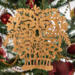 A handcrafted Victorian-style wooden Christmas tree ornament shaped like a basket filled with intricate floral designs, featuring detailed leaves and blossoms, with a small hook at the top for hanging.