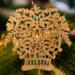 A handcrafted Victorian-style wooden Christmas tree ornament shaped like a basket filled with intricate floral designs, featuring detailed leaves and blossoms, with a small hook at the top for hanging.