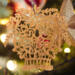 A handcrafted Victorian-style wooden Christmas tree ornament shaped like a basket filled with intricate floral designs, featuring detailed leaves and blossoms, with a small hook at the top for hanging.