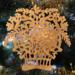 A handcrafted Victorian-style wooden Christmas tree ornament shaped like a basket filled with intricate floral designs, featuring detailed leaves and blossoms, with a small hook at the top for hanging.