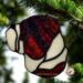 Bulldog stained glass ornament in brindle shown hanging on a Christmas tree.