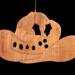 Handmade wooden Christmas tree ornament shaped like a cowboy hat, featuring a sprig of holly tucked into the hat band, star-shaped leaf cutouts, and round berry accents.