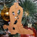 Handmade wooden Christmas tree ornament shaped like a cowboy boot, featuring a sprig of holly On the side of the boot, and round berry accents.