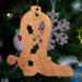 Handmade wooden Christmas tree ornament shaped like a cowboy boot, featuring a sprig of holly On the side of the boot, and round berry accents.