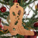 Handmade wooden Christmas tree ornament shaped like a cowboy boot, featuring a sprig of holly On the side of the boot, and round berry accents.