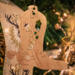 Handmade wooden Christmas tree ornament shaped like a cowboy boot, featuring a sprig of holly On the side of the boot, and round berry accents.