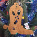 Handmade wooden Christmas tree ornament shaped like a cowboy boot, featuring a sprig of holly On the side of the boot, and round berry accents.