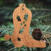 Handmade wooden Christmas tree ornament shaped like a cowboy boot, featuring a sprig of holly On the side of the boot, and round berry accents.