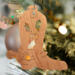 Handmade wooden Christmas tree ornament shaped like a cowboy boot, featuring a sprig of holly On the side of the boot, and round berry accents.