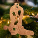 Handmade wooden Christmas tree ornament shaped like a cowboy boot, featuring a sprig of holly On the side of the boot, and round berry accents.