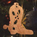 Handmade wooden Christmas tree ornament shaped like a cowboy boot, featuring a sprig of holly On the side of the boot, and round berry accents.