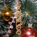Handmade wooden Christmas tree ornament shaped like a peppermint stick with diagonal stripes, crafted from light-colored wood with flared decorative ends.