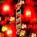 Handmade wooden Christmas tree ornament shaped like a peppermint stick with diagonal stripes, crafted from light-colored wood with flared decorative ends.