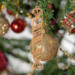 Handmade wooden Christmas tree ornament shaped like a peppermint stick with diagonal stripes, crafted from light-colored wood with flared decorative ends.