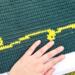 A close up of one of the yellow swirls that appear above and below the quote. The maker's hand is in the photo for size context.  A close up of one of the yellow swirls that appear above and below the quote. The maker's hand is in the photo for size context.