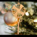 A handcrafted wooden Christmas tree ornament shaped like a lollipop, featuring intricate cut-out spiral patterns on the circular top and a simple stick base. The ornament is light brown with a smooth finish.
