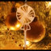 A handcrafted wooden Christmas tree ornament shaped like a lollipop, featuring intricate cut-out spiral patterns on the circular top and a simple stick base. The ornament is light brown with a smooth finish.
