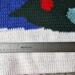 A close up of the right side of the blanket which shows snow, a blue background, and the bottom part of the Christmas tree. 