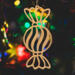 A handmade wooden Christmas tree ornament shaped like a wrapped hard candy, featuring a bulbous center with swirling stripes and twisted wrapper ends, crafted from light-toned wood using a scroll saw.