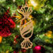 A handcrafted wooden Christmas tree ornament shaped like a wrapped candy, featuring intricate Victorian fretwork with twisted ends and a diagonal swirling stripe in the center.