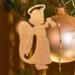 A handmade wooden Christmas ornament in the shape of a cheerful angel, featuring a halo, wings, and a raised arm ringing a bell, hand-cut from solid hardwood and finished with clear shellac.