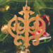 Intricate Victorian-style fretwork Christmas tree ornament handcrafted from natural hardwood with visible wood grain, showcasing symmetrical curls, loops, and ornate cut-out designs.