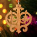 Intricate Victorian-style fretwork Christmas tree ornament handcrafted from natural hardwood with visible wood grain, showcasing symmetrical curls, loops, and ornate cut-out designs.
