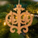 Intricate Victorian-style fretwork Christmas tree ornament handcrafted from natural hardwood with visible wood grain, showcasing symmetrical curls, loops, and ornate cut-out designs.