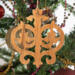 Intricate Victorian-style fretwork Christmas tree ornament handcrafted from natural hardwood with visible wood grain, showcasing symmetrical curls, loops, and ornate cut-out designs.