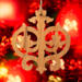 Intricate Victorian-style fretwork Christmas tree ornament handcrafted from natural hardwood with visible wood grain, showcasing symmetrical curls, loops, and ornate cut-out designs.