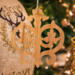 Intricate Victorian-style fretwork Christmas tree ornament handcrafted from natural hardwood with visible wood grain, showcasing symmetrical curls, loops, and ornate cut-out designs.