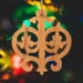 Intricate Victorian-style fretwork Christmas tree ornament handcrafted from natural hardwood with visible wood grain, showcasing symmetrical curls, loops, and ornate cut-out designs.