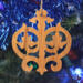 Intricate Victorian-style fretwork Christmas tree ornament handcrafted from natural hardwood with visible wood grain, showcasing symmetrical curls, loops, and ornate cut-out designs.