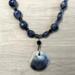 Frontal view of deep blue sodalite beads, Czech crystals, and ceramic shell pendant with blue-brown ridges
