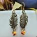 Handmade brass leaf earrings with glass seed beads on a jump ring and 14K gold earring wires, 2 inches long.
