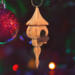 Handcrafted miniature wooden birdhouse ornament shaped like an icecicle with a pointed roof and base, featuring a rounded entrance hole and a perched bird, and made from reclaimed hardwoods finished with a satin shellac.