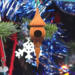 Handcrafted miniature wooden birdhouse ornament shaped like an icecicle with a pointed roof and base, featuring a rounded entrance hole and a perched bird, and made from reclaimed hardwoods finished with a satin shellac.