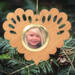 Wooden heart-shaped ornament with scalloped edges and an oak grain finish, featuring a removable round gold frame that holds a photo of a smiling blonde child.