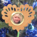 Wooden heart-shaped ornament with scalloped edges and an oak grain finish, featuring a removable round gold frame that holds a photo of a smiling blonde child.