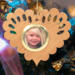 Wooden heart-shaped ornament with scalloped edges and an oak grain finish, featuring a removable round gold frame that holds a photo of a smiling blonde child.