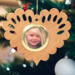 Wooden heart-shaped ornament with scalloped edges and an oak grain finish, featuring a removable round gold frame that holds a photo of a smiling blonde child.