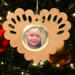 Wooden heart-shaped ornament with scalloped edges and an oak grain finish, featuring a removable round gold frame that holds a photo of a smiling blonde child.
